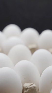 El yumurtaları bir kutuya koyar. Yumurtalar tepsiye istiflenmiş. Dikey video