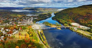 Sonbaharda Vermont, New England, ABD 'nin çarpıcı manzarası. Sakin nehrin üzerindeki köprüye bakın. Havadan bakış açısı. Şehrin üzerinde bulutlu bir gökyüzü.