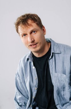 İçerideki mavi gömlekli adam. Kapalı bir yerde oturan bir adam siyah bir tişörtün üzerine mavi bir gömlek giymiş ve yüzünde düşünceli bir ifade var..