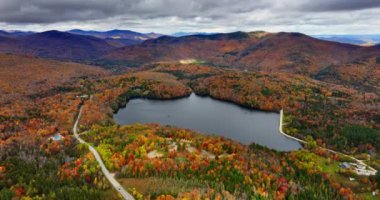 Vermont, New England, ABD 'de sonbahar. Dağların eteğindeki göle hava perspektifi. Manzaranın üzerindeki bulutlu gri gökyüzü.