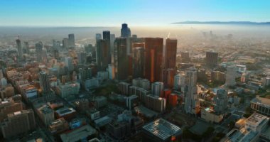 Sisli bir günde Los Angeles 'ın finans merkezindeki bir grup gökdelene yaklaşıyoruz. Arka planda göz kamaştıran sisli şehir manzarası. Üst görünüm.