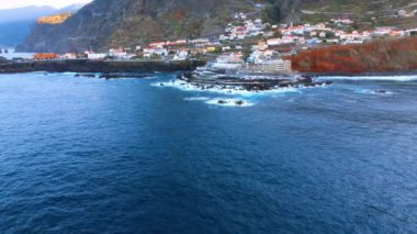 Portekiz, Madeira 'nın kayalık kıyılarına daha yakın uçuyor. Yüksek dağların yamaçlarındaki yerleşim yerlerinin görüş açısı düşük..