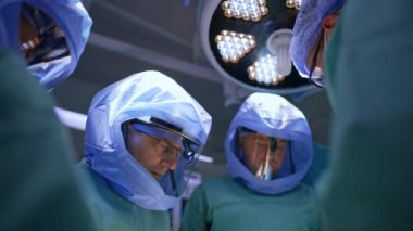 Ameliyat masasını çevreleyen doktorlar operasyonda koruyucu kask takarlar. Travma cerrahisinde ilerleme.