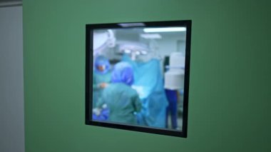 Ameliyathanenin kapısındaki kare pencere. Doktorlar ameliyathanede çalışıyor. Bulanık arkaplan.