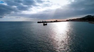 Eski geminin silueti gün batımında iskeleye yaklaşıyor. Portekiz, Madeira sahiline varıyor..