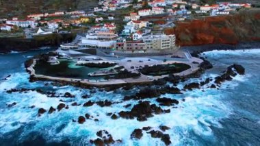 Madeira 'nın güzel kıyıları, gün batımında Portekiz. Kıyı şeridinde, kayalıklarda birden fazla kır evi olan insansız hava aracı görüntüleri..