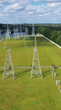 Elektrik kuleleri olan bir alanda panoramik manzara. Kırsal kesimde yeşil doğanın arka planında kabloları olan yüksek voltajlı elektrik hatları. Dikey video