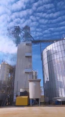 Çağdaş tarım fabrikası. Dışarıda tahıl işlemek için çelik asansörler. Sanayiden gökyüzünü kaplayan beyaz duman. Aşağıdan bak. Dikey video