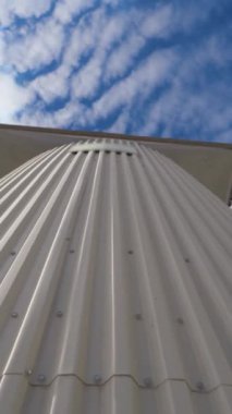 Modern fabrikanın metal inşaatı. Arkaplanda tahıl işlemek için depolama tankları. Endüstriden çıkan duman havaya karışıyor. Yakın plan. Hareket kamerasının üstünü indir. Dikey video