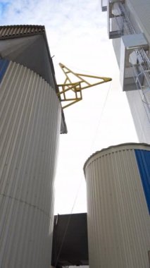 Modern bir fabrikanın dışı. Tarımsal ürünleri işlemek ve kurutmak için büyük bir ambar. Tahıl asansörü açık havada. Yakın plan. Dikey video