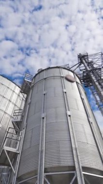 Tahıl deposu için modern endüstriyel tahıl asansörleri. Çelik silolar, güzel gökyüzü arka planına karşı bir tarım çiftliğinde tahıl depolamak için. Yakın plan. Dikey video