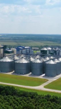 Sahada modern bir bitki. Zirai ürünleri işlemek için tarım ve imalat tesisinde gümüş silolar. Hava görüntüsü. Hareket kamerası geri. Dikey video