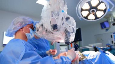 Dikkatli bir beyin cerrahı mikroskop kullanarak ameliyat yapar. Modern hastanede beyin cerrahisi.