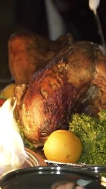 Şef, fırında pişirilmiş tavuğu bıçakla kesiyor ve dilimleri tabağa koyuyor. Sokağın yanındaki kafede dikey videonun yaz terasında.