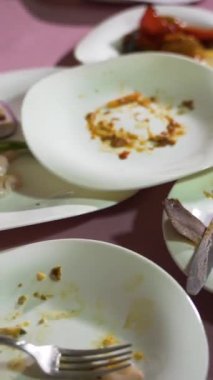 Tabakların kalıntılarıyla birlikte beyaz porselen tabaklar kafedeki masanın üzerindeki pembe bir masa örtüsünün üzerinde. Sağ dikey video için kamera hareketi