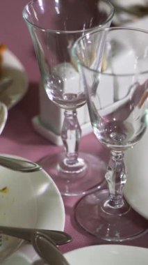 Bulaşık kırıntıları, tatilden sonra restoranda pembe arka planda beyaz tabaklarda. Arta kalan dikey video