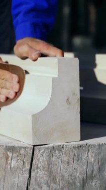 Usta, öğleden sonra sokağın ortasında bir kütüğün üzerinde, zümrüt bir bezle ahşap bir ürünü cilalıyor. Dikey video
