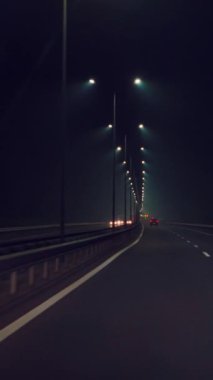 Araba karanlıkta otoyol boyunca hızla gidiyor. Arabayla gece yolculuğu. Hareket hızı Dikey video