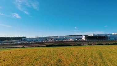 Büyük bir sanayi bölgesinden ayrılan sarı tarım arazisi. Devasa modern fabrika boyunca insansız hava aracı görüntüleri.