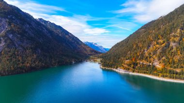 Avrupa 'daki dağların arasına kurulmuş güzel bir göl. Sakin bir göl, heybetli dağlarla çevrili mavi gökyüzünü ve huzurlu bir günde renkli sonbahar yapraklarını yansıtır..