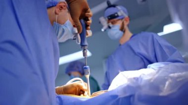 Kahverengi lateks eldivenli bir cerrah beyin cerrahisinde tornavida kullanır. Düşük açı. Doktor hemşireye bir enstrüman verir.