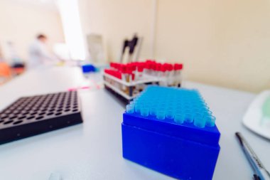 Laboratuvar araştırmalarında renkli test tüpleri. Bir laboratuvar kurulumu, aktif bilimsel araştırmaların devam ettiğini gösteren, raflarda düzenlenmiş canlı test tüpleri içerir..