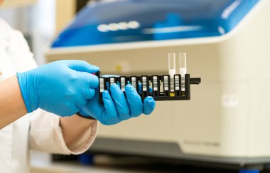 Laboratuvardaki test tüplerini teknik ekip yönetiyor. Eldivenli bir laboratuar teknisyeni bilimsel bir deney sırasında bir araştırma tesisinde test tüplerini dikkatlice yönetir..