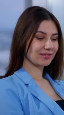 Mavi ceketli, bir elinde telefon, diğerinde gözlük tutan pozitif, rahat bir iş kadını. Bayan aletinin ekranından okuyor ve sonra kameraya bakıyor. Dikey video