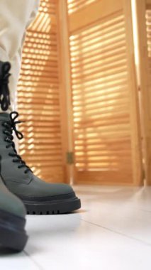 Bağcıklı ve traktör tabanlı gri kadın asker botlarının stüdyo gösterisi. Açık kotlu kadın ayakkabıları kameraya yakın gösteriyor. Dikey video