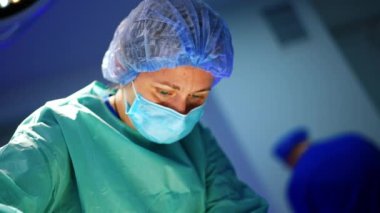 Kadın cerrah ameliyat yerine dikkatle bakıyor. Ameliyat yapan çalışkan profesyonel bir doktorun portresi. Düşük açı görünümü.