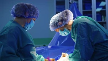 Kadın doktor iş yerinde metal aletler kullanıyor. İki doktor tarafından yapılan cerrahi operasyonun ilerlemesi.