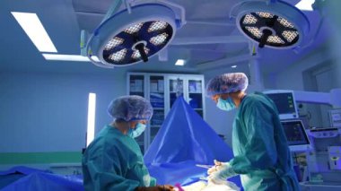 Kadın sıhhiyeciler ameliyathanedeki yuvarlak lambaların altında duruyorlar. Modern hastanedeki doktorlar tarafından gerçekleştirilen bir operasyon..