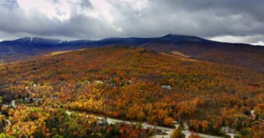 Vermont, New England, ABD 'deki dağlık araziyi turuncu ağaçlar kaplar. Gri bulutlar kayalarda yuvarlanır. Hava görünümü.