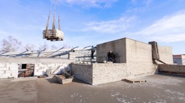 İki adam aletleri kullanarak binanın tepesinde çalışıyor. Bir evin çatısının yapımı..