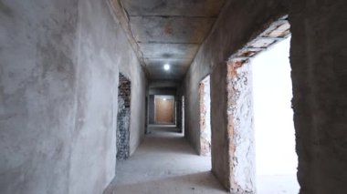 Kapı aralıkları olan uzun koridorda ilerliyorlar. Bitmemiş binada yapım aşamasında olan bir yürüyüş..