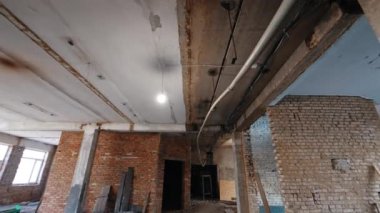 Tavanda asılı plastik boru, elektrik teli ve ampulle birlikte. Düşük açı. Binadaki oda yeniden inşa ediliyor..