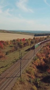 Yük treni, kırsal kesimin arka planındaki en yakın kasabaya demiryolu ile ilerliyor. Hava görünümü