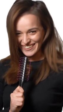 Saçını tarak tarayan bir kız. Sağlıklı ve parlak saçlarını tarayan güzel genç bir kadın, stüdyo beyazı.