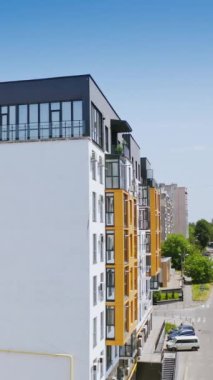 Güneşli gündüz vakti şehir geçmişi. Yeni bir apartmanın dışında. Geniş pencereli ve balkonlu yüksek binaların modern tasarımı. Dikey video