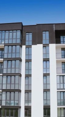 Çok katlı güzel bir binanın ön manzarası. Birçok cam pencere ve balkonlu yüksek katlı apartmanın modern tasarımı. Hava görüntüsü. Dikey video