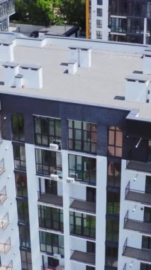 Şehir sakinleri için yeni bir ev. Geniş pencereleri ve dış görünüşü güzel duvarları olan çağdaş bir apartman. Şehir manzarası yüksek bir binanın camlarına yansıyor. Hava görüntüsü. Dikey video