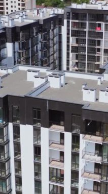 Çocuk parkı olan modern şehir kompleksi. Modern binalarla dolu yüksek konut kompleksinin üzerinden uçmak. Şehirde yeni bir altyapı. Hava görüntüsü. Dikey video