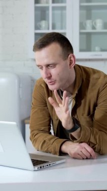 Freelancer mutfakta dizüstü bilgisayar üzerinde çalışıyor. Yakışıklı adam evde mutfak masasında otururken bir video görüşmesi yapıyor. Öğrenci çevrimiçi çalışıyor. Dikey video