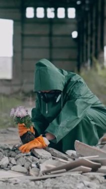 Ekolojist taşlara çiçek eker. Gaz maskeli bir adam çevresel bir felaketten sonra tesisi koruyor. Kimyasal saldırı. Dikey video