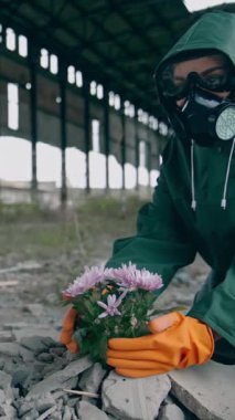 Ekolojik bir felaket. Koruyucu giysi ve gaz maskeli bir ekolojist, kimyasal saldırıyla ıssız bir yerdeki çiçekleri kurtarmaya çalışıyor. Dikey video