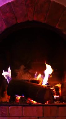 Odunlar şöminede yanıyor. Modern tasarımlı güzel tuğlalı şömine. Kışın evde rahatlık ve konfor. Dikey video