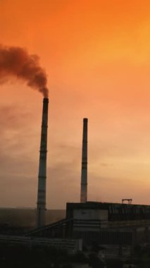 Kimya endüstrisi tarafından çevresel zehirlenme. Fabrika bacaları havaya büyük dumanlar üflüyor. Yüksek pipodan gelen siyah duman akşam doğasının arka planına karşı. Dikey video