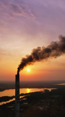 Endüstriyel borudan kaynaklanan tehlikeli hava kirliliği. Gün batımında kırsal kesimde zararlı dumanı olan bir elektrik santrali. Hava emisyonu kirliliği konsepti. Dikey video