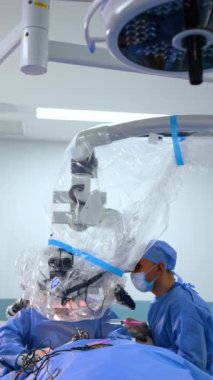 Modern teknolojik mikroskop ameliyat masasının üzerinde hazır. Cerrahlar dürbüne bakarak ameliyat yaparlar. Dikey video.