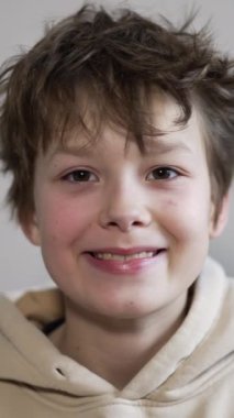 Gülümseyen esmer beyaz erkek portresi. Kapüşonlu bir genç kameraya bakarken dişlerini gösteriyor. Kapatın. Dikey video